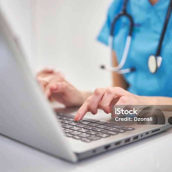 istockphoto-1399172596-1024x1024 Close-up hands of unrecognizable female physician in medical uniform working typing on laptop keyboard sitting at desk